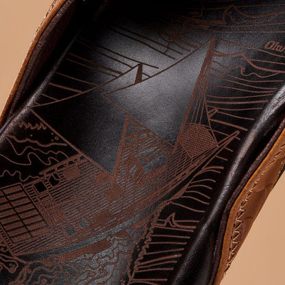 The insole of the Olukai Men's Hikianalia Tan Dark Java sandals features a detailed sailboat design against a dark background.