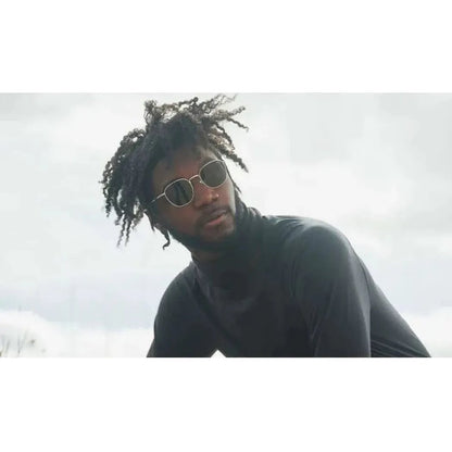 A model wearing the Optic Nerve Townsend sunglasses in a low-angle shot against a cloudy sky.