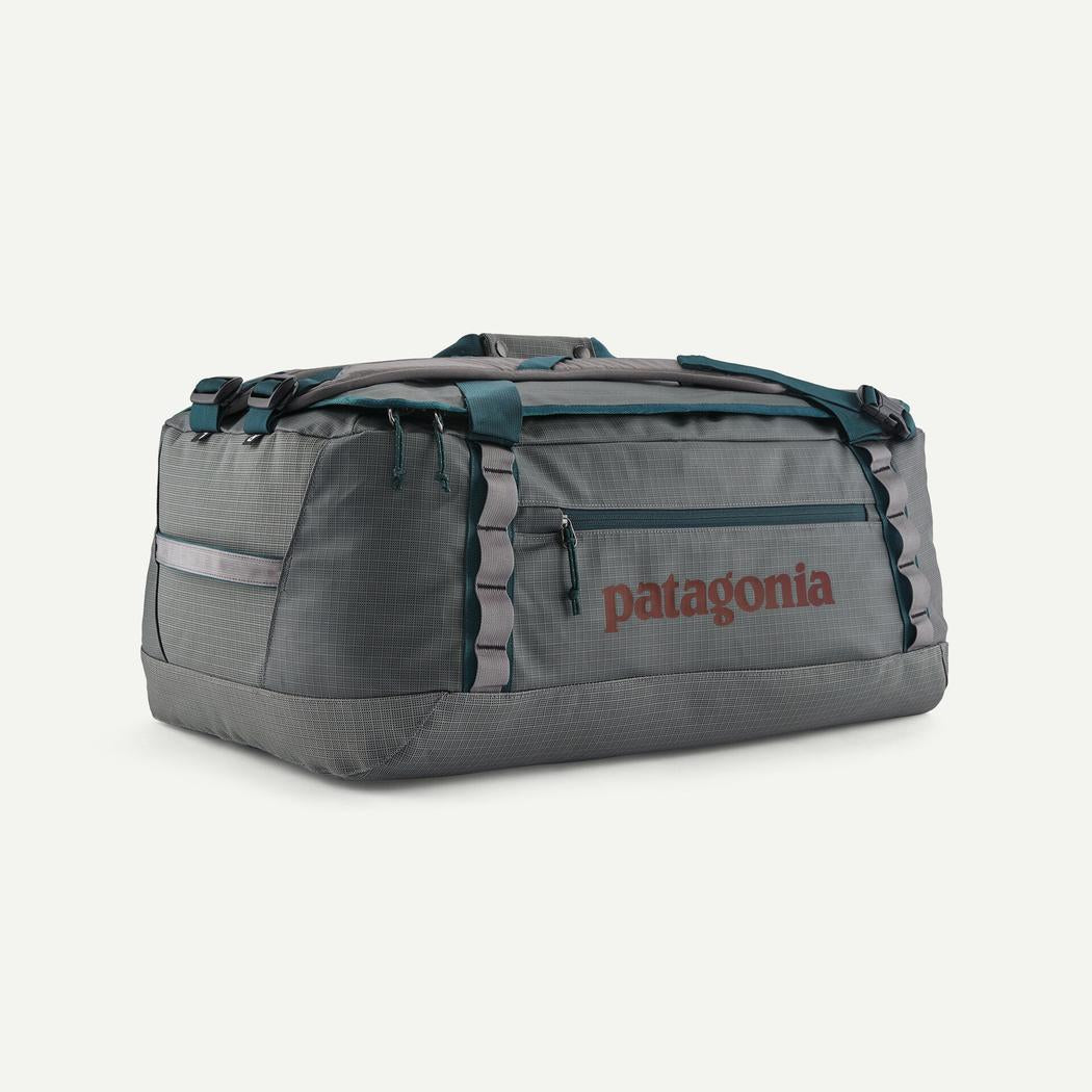 A front view of the Patagonia Black Hole Duffel 55L in Black w/Black with a gray front pocket and teal straps against a white background.