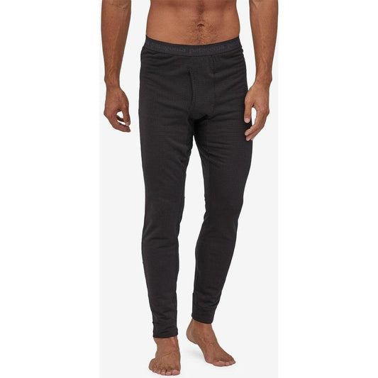 A front view of the Patagonia Men's Capilene Thermal Weight Bottoms in Black on a barefoot model against a white background.