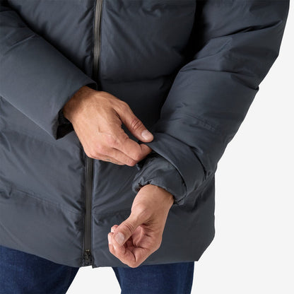 A close-up of the Patagonia Men's Jackson Glacier Parka in Black, showing the model adjusting the sleeve cuff against a plain white background.