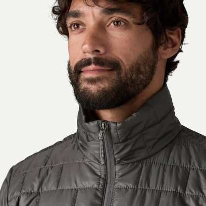 A front view of the Patagonia Men's Nano Puff Jacket in Forge Gray with a high collar and zipper, worn by a model against a plain white background.