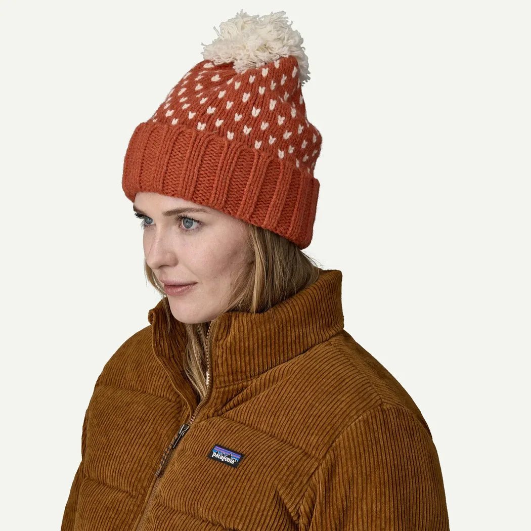 A woman wears the Patagonia Snowbelle Beanie in Offset Dot: Burnished Red, shown from the side against a plain white background.