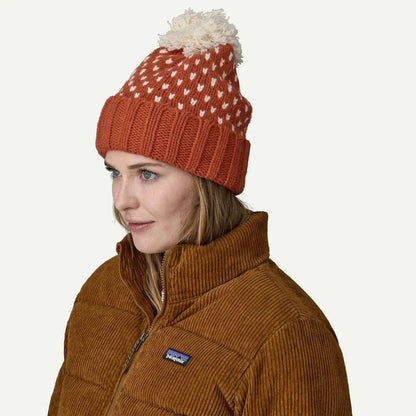 A woman wears the Patagonia Snowbelle Beanie in Offset Dot: Burnished Red, shown from the side against a plain white background.