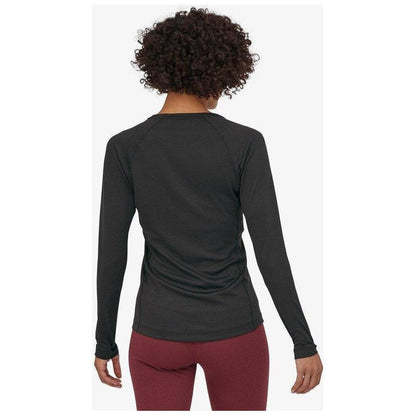 Back view of the Patagonia Women's Capilene Midweight Crew in Black on a model wearing maroon pants against a white background.