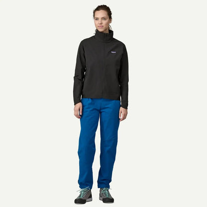 A woman wearing the Patagonia Women's R1 CrossStrata Jacket in Black stands against a plain white background.