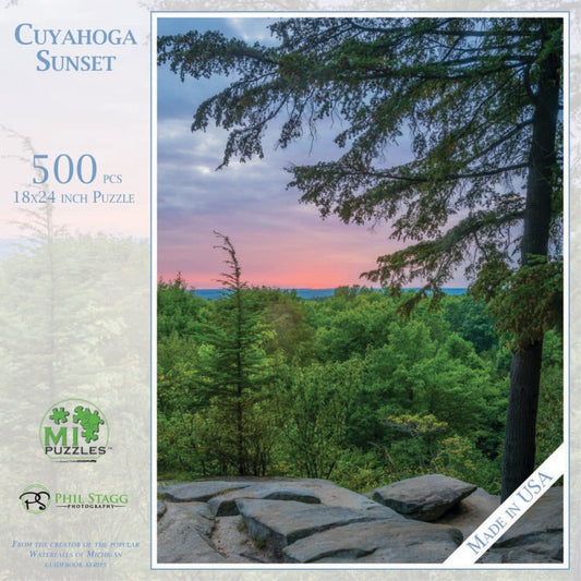 A 500 piece Cuyahoga Sunset puzzle by Phil Stagg Photography shows a sunset over a forest with rocks in the foreground.