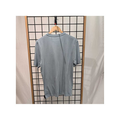 Back view of the Prana Mens Bear Squeeze Journeyman SS Tee-SAMPLE in Glacier Sky hanging on a wooden hanger against a grid background.