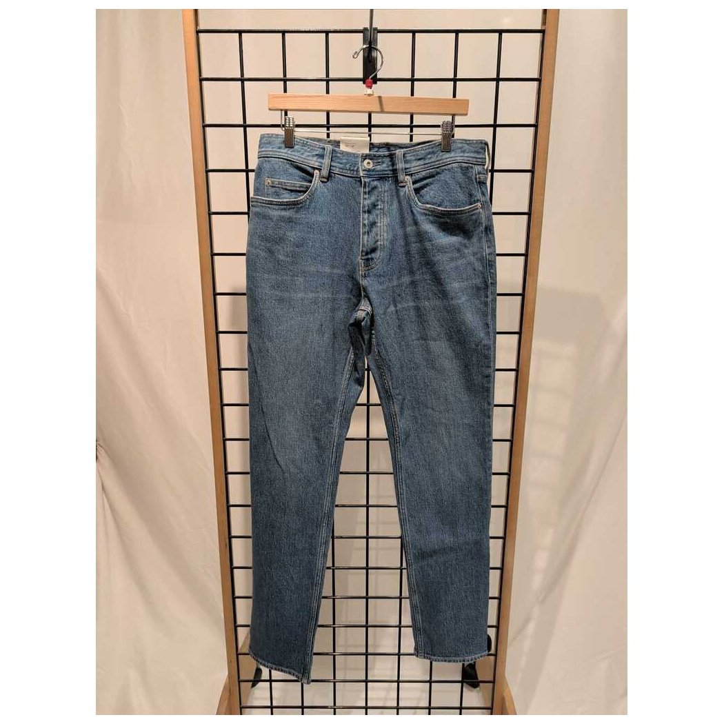 Front view of the Prana Mens Carlsbad 760 Slim Jeans-SAMPLE in Sea Salt/32 hanging on a grid display with a wooden hanger.