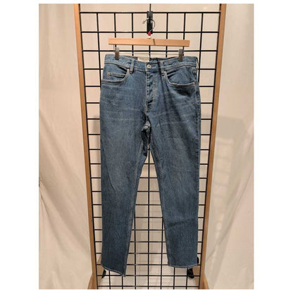 Front view of the Prana Mens Carlsbad 760 Slim Jeans-SAMPLE in Sea Salt/32 hanging on a grid display with a wooden hanger.