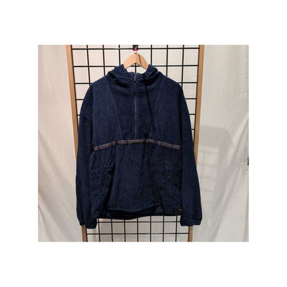 Front view of the Prana Mens Durado Cord Anorak-SAMPLE in Capulet Blue hanging on a wooden hanger against a grid background.