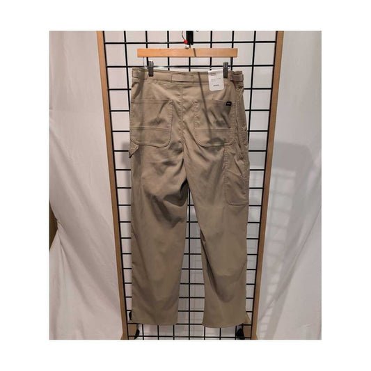Front view of the Prana Mens Stretch Zion Carpenter Pant-SAMPLE in Sandbar/32 hanging on a grid display with a white backdrop.