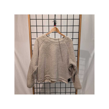 Front view of the Prana Womens Encinitas Sherpa Crew-SAMPLE in Almond hanging on a wooden hanger against a grid backdrop.