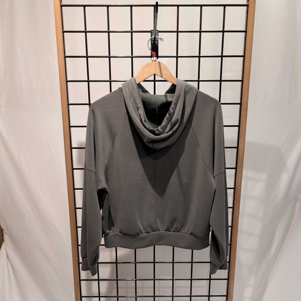 Back view of the Prana Womens Shae Full Zip-SAMPLE in Thyme hanging on a wooden hanger against a grid background.