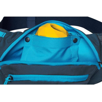 A close-up of the Ruffwear Home Tail Hip Pack in Aurora Teal showing the front pocket with a yellow item inside and a zippered compartment below.