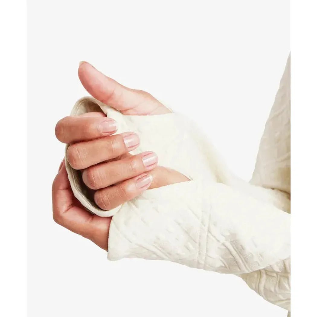 A close-up of the Sherpa Adventure Gear Women's Nyano Pullover in Ecru, showing the soft fabric and a model's hands holding it against a plain white background.