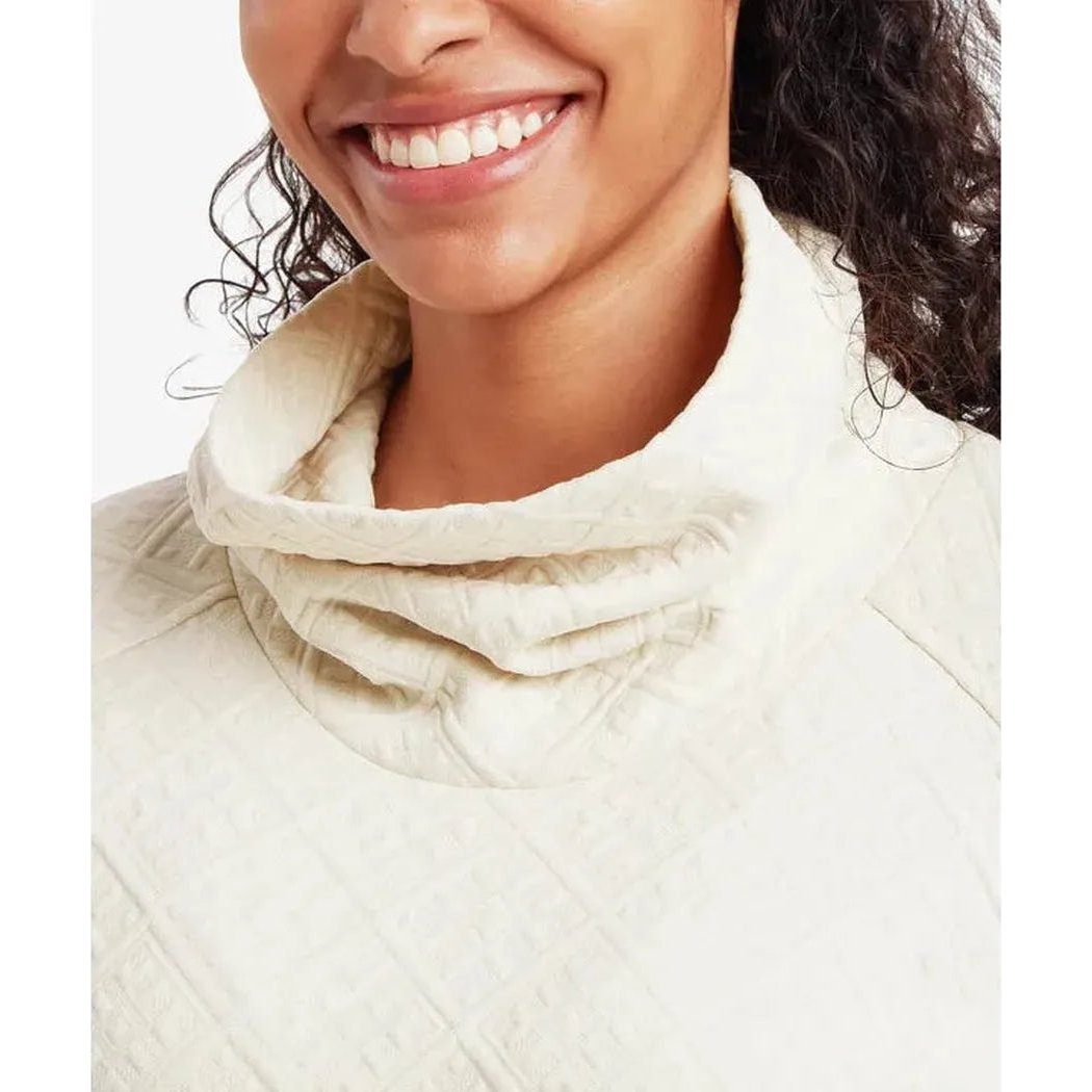A close-up of the Sherpa Adventure Gear Women's Nyano Pullover in Ecru, showing the high collar and textured fabric on a smiling model against a plain white background.