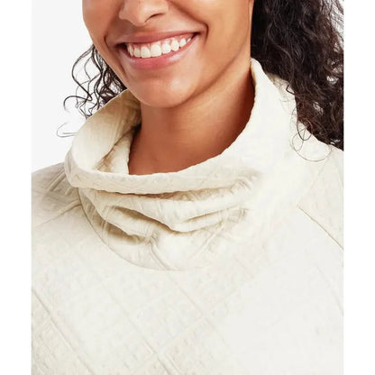 A close-up of the Sherpa Adventure Gear Women's Nyano Pullover in Ecru, showing the high collar and textured fabric on a smiling model against a plain white background.