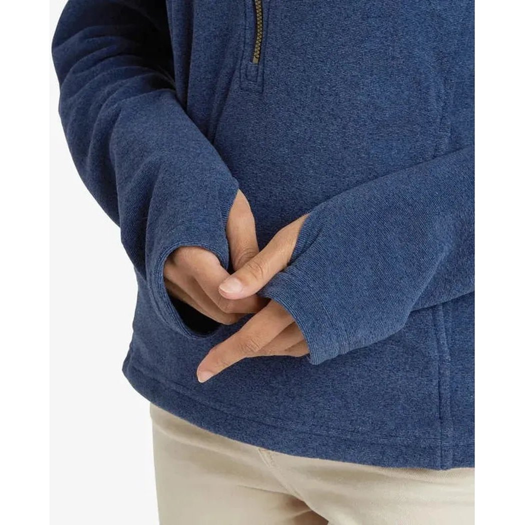 A close-up of the Sherpa Adventure Gear Women's Rolpa Eco Pullover Zip in Rathee Blue, showing the half-zip and model's hands against a plain white background.
