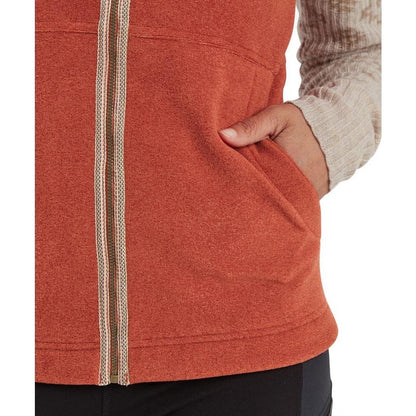A close-up of the Sherpa Adventure Gear Women's Rolpa Eco Vest in Rust, showing the front zipper and a hand in the pocket.