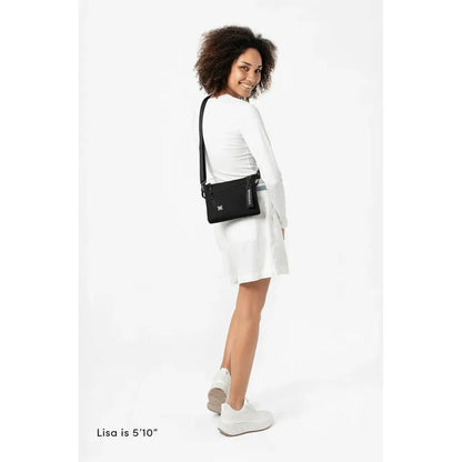 A model wearing the Sherpani Zoom Con Leche bag in a side view against a white background.