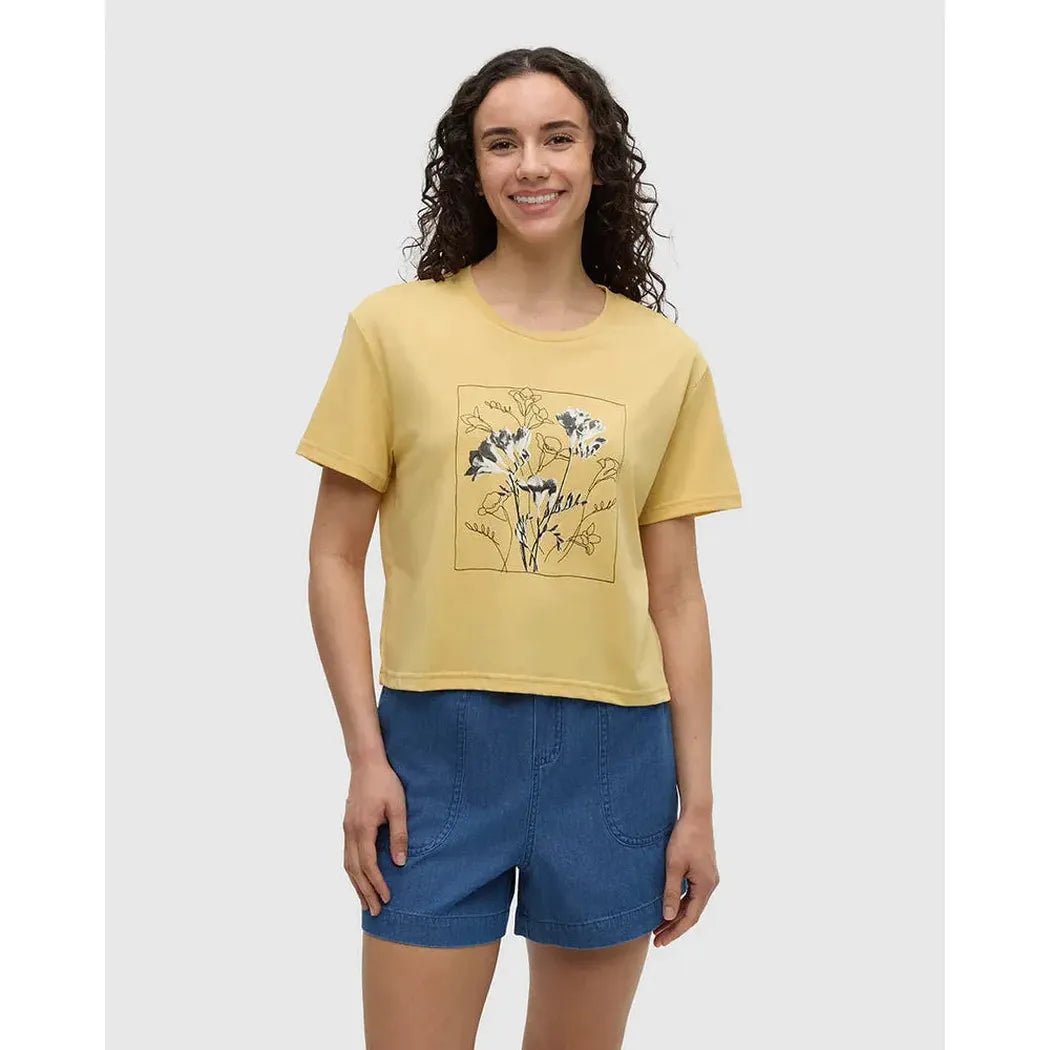 A front view of the Tentree Women's Floral Crop T-Shirt in Dusk Yellow Meteorite Black on a model wearing blue shorts against a white background.