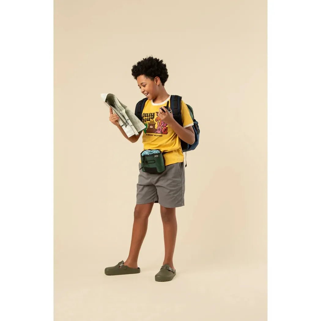 A youth wearing The Landmark Project Only You Vintage Youth Short Sleeve Ringer Tee in Sunshine/Honeycomb looks at a map while standing against a plain background.