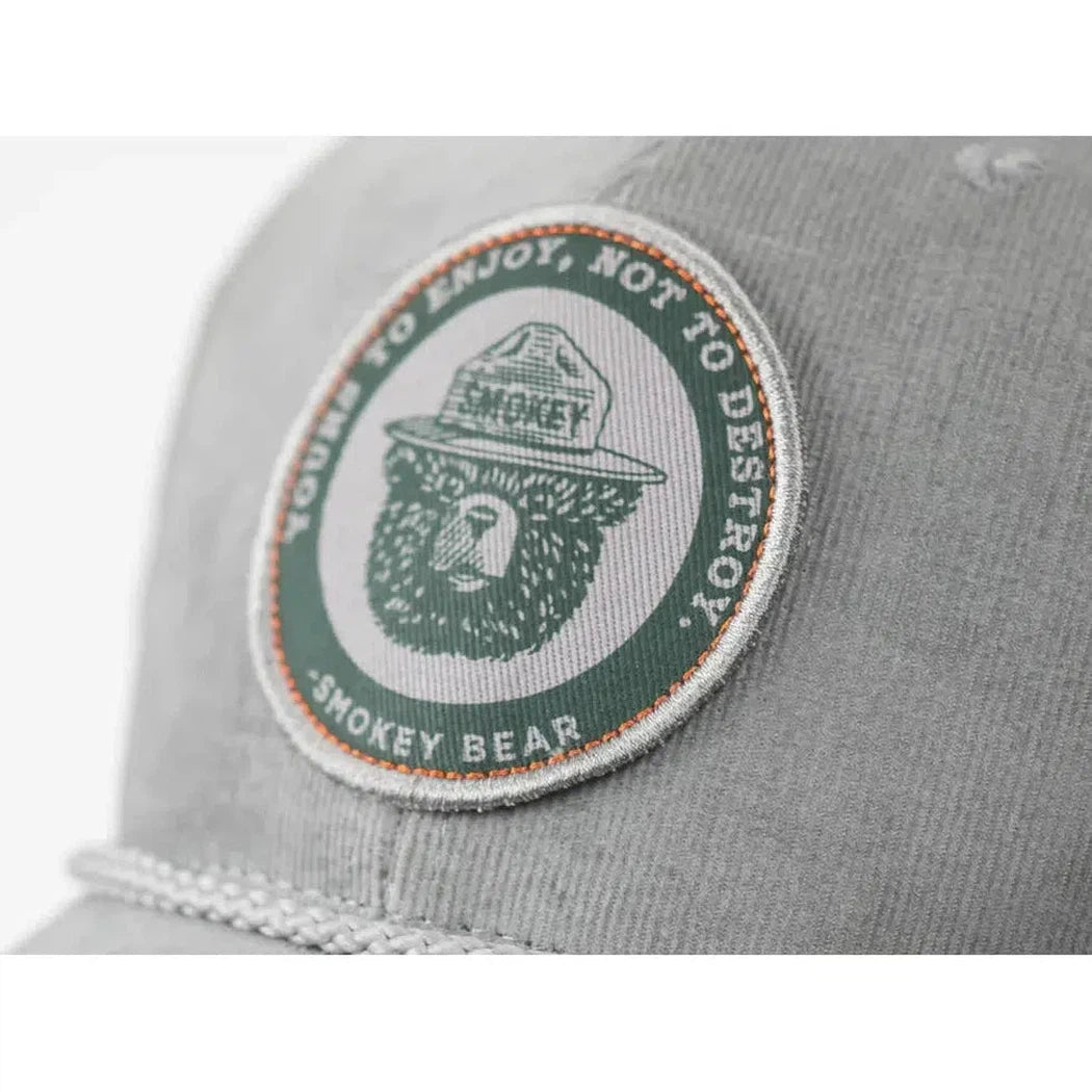 A close up of the grey The Landmark Project Yours to Enjoy Hat showing the Smokey Bear patch on the front.
