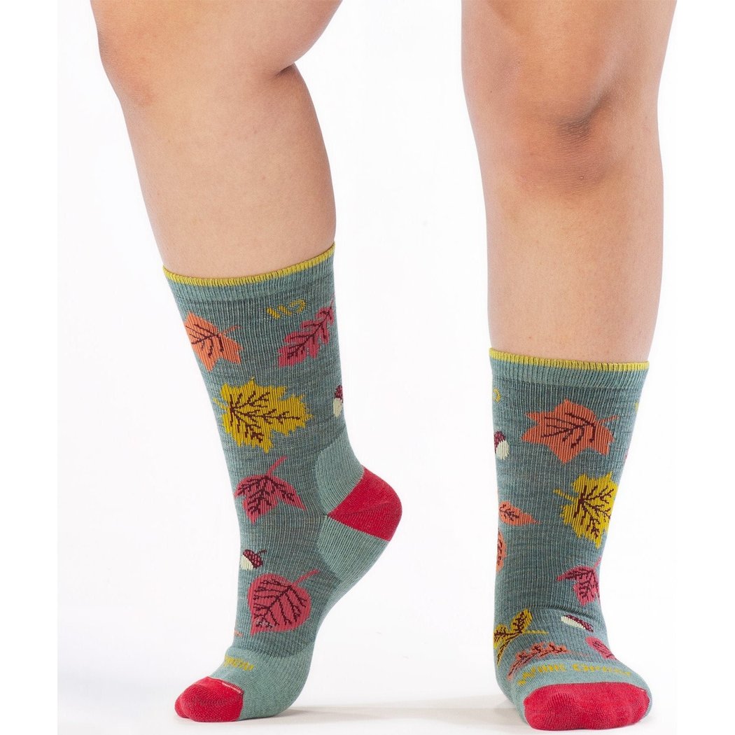 Close-up of Wide Open Women's Fall In Love Cushioned Crew Socks in Seafoam with leaf patterns and red toes on a model's legs against a white background.