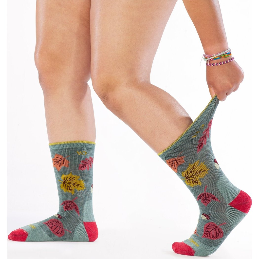 Side view of the Wide Open Women's Fall In Love Cushioned Crew Socks in Seafoam showing a model pulling one sock up against a white background.