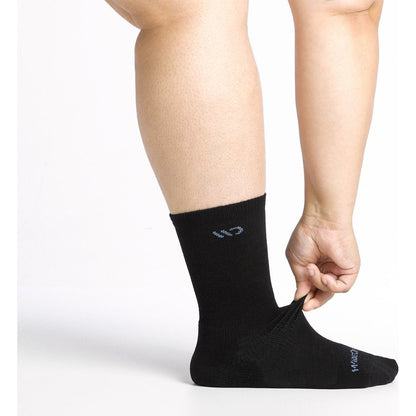 Close-up of a model wearing the Wide Open Women's Solid Cushioned Crew Socks in Black with a hand adjusting the sock against a white background.