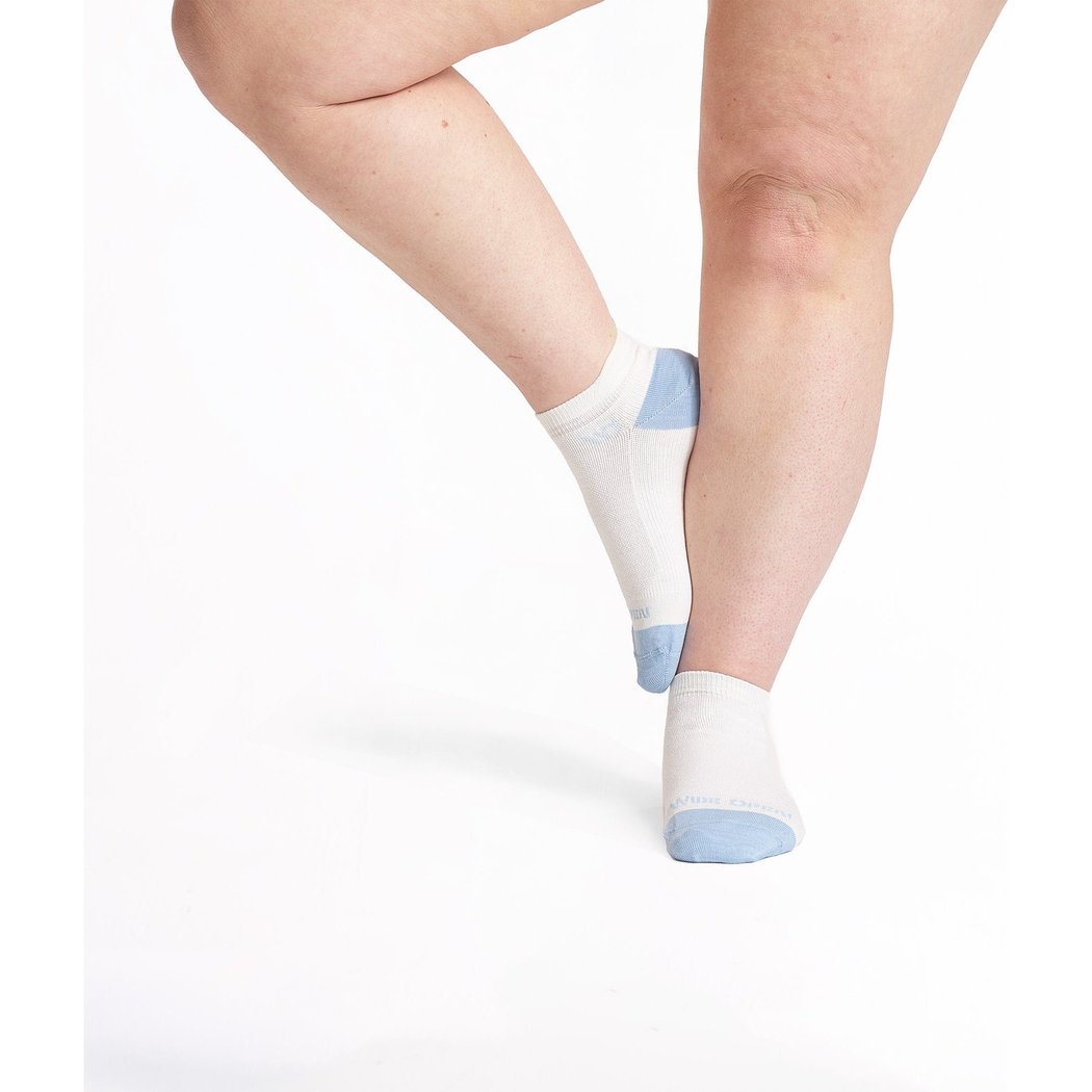 Close-up of a model wearing White Wide Open Women's Solid No Cushion Ankle Socks with light blue toe and heel accents against a white background.