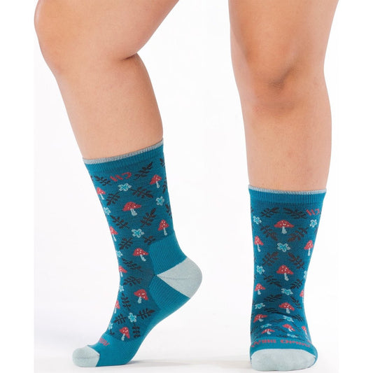 Close-up of a model wearing Wide Open Women's Wildwood Cushioned Crew Socks in Bright Teal with a mushroom and leaf pattern against a white background.