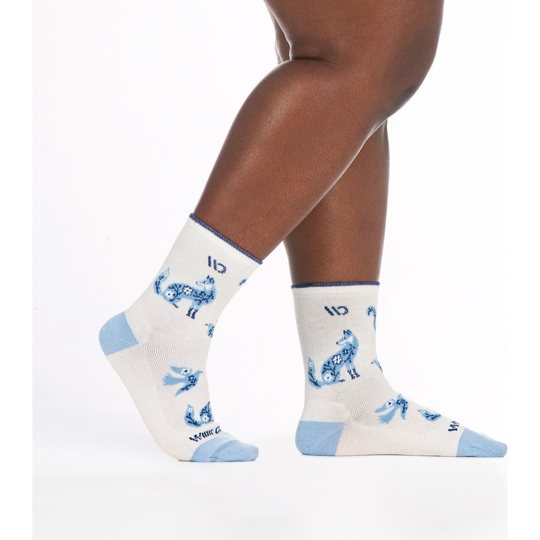 Close-up of a model’s legs wearing Wide Open Women's Woodland Wonder No Cushion Micro Crew Socks in Teal with blue woodland animal prints against a white background.