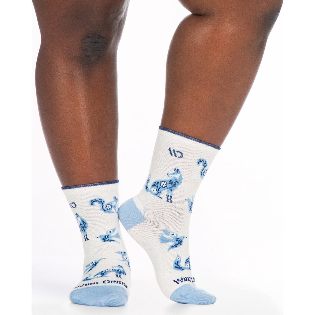 Close-up of a model wearing Wide Open Women's Woodland Wonder No Cushion Micro Crew Socks in Teal with blue woodland animal prints against a white background.