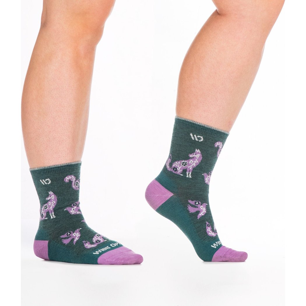 Close-up of a model wearing Wide Open Women's Woodland Wonder No Cushion Micro Crew Socks in Teal with purple toes and wolf patterns against a white background.